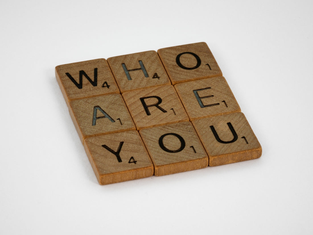 Wooden Scrabble tiles arranged in a grid spelling the words WHO ARE YOU