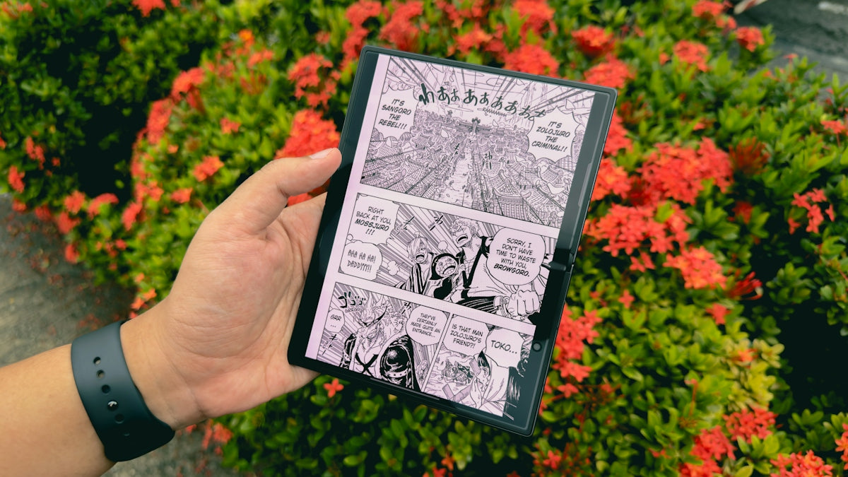 A hand holds a device showing manga with red flowers
